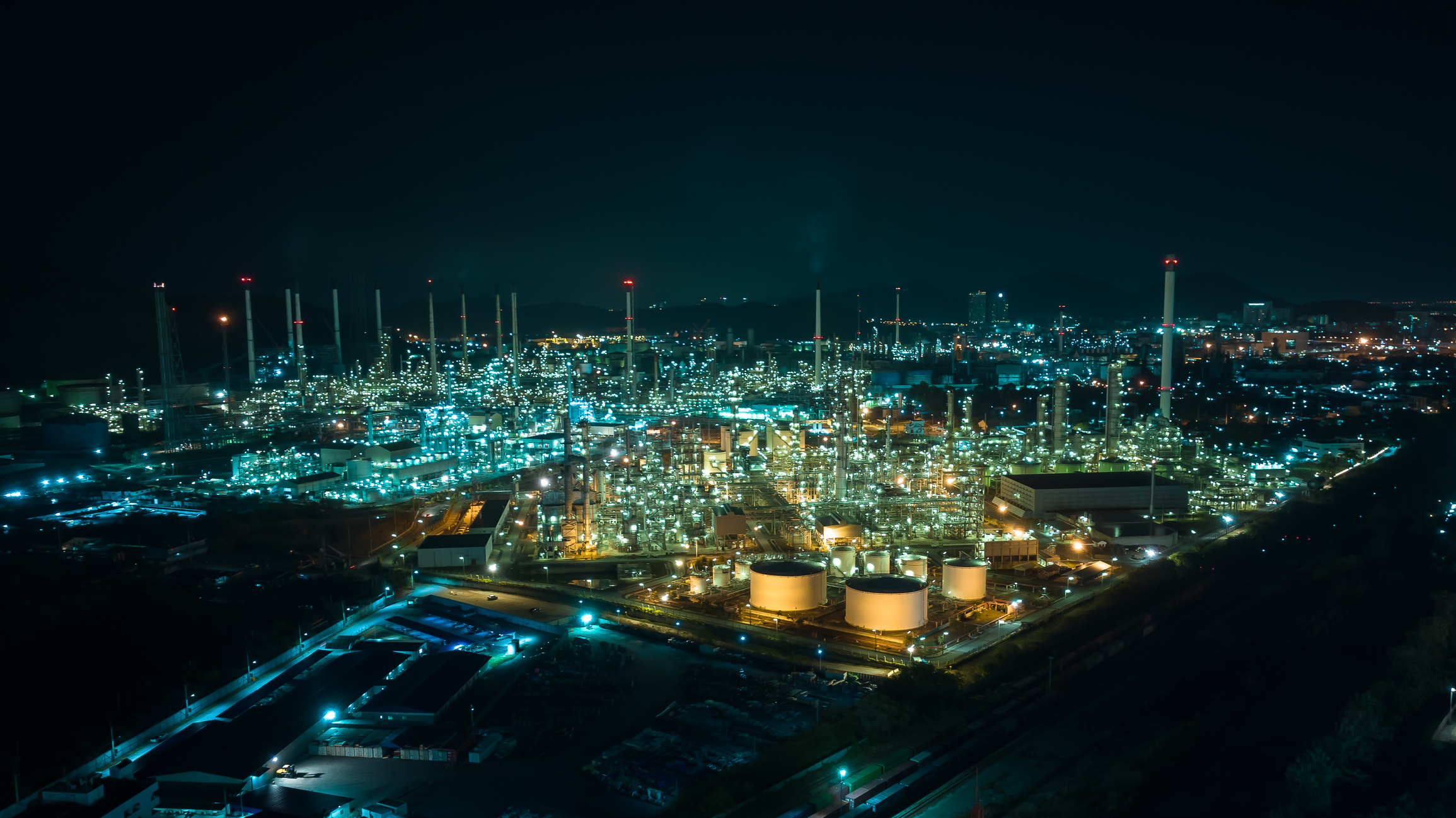 Oil refinery plant from industry zone, Aerial view oil and gas petrochemical industrial, Refinery factory oil storage tank and pipeline steel at night over lighting, drone shot